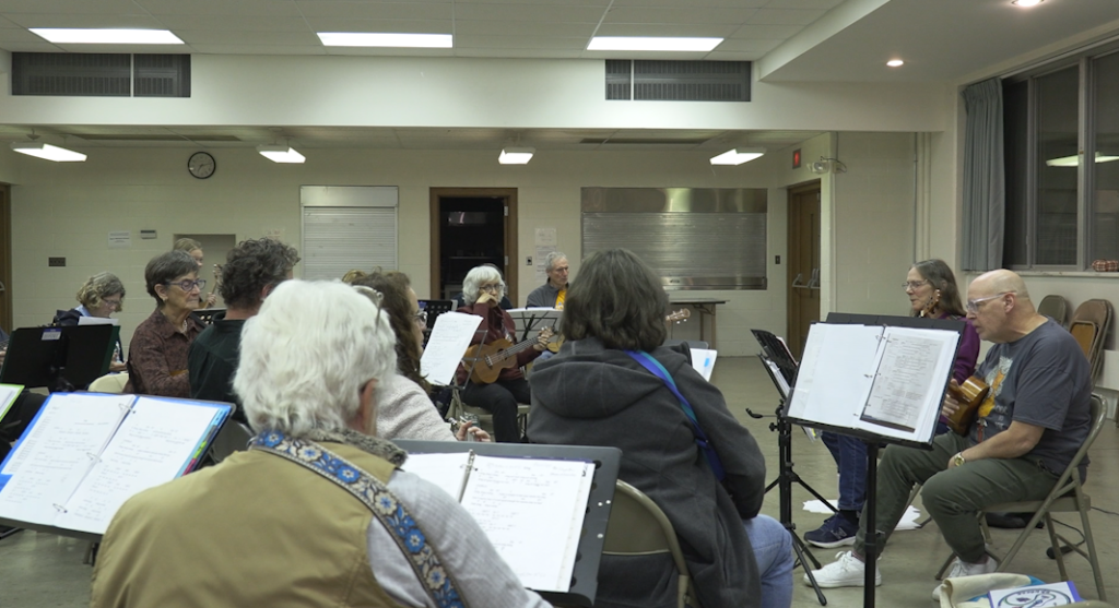 Group of people gathered in a semi-circle practicing a musical instrument.